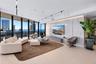 Floor-to-ceiling windows featuring panoramic city and water scenery, light-toned wood-finish flooring, large-format stone feature wall with integrated