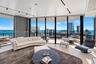 Floor-to-ceiling glass walls, expansive wrap-around balcony, light-toned wood-finish flooring, and industrial-style track lighting