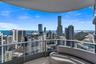 Covered balcony with a curved structural layout, featuring a glass-panel railing and panoramic urban and water scenery