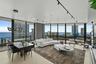 Open-concept interior featuring floor-to-ceiling glass windows, recessed track lighting, a geometric chandelier, and light-toned flooring