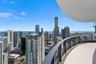 Curved balcony featuring light-colored tile flooring and a glass-paneled railing overlooking an expansive cityscape and water horizon