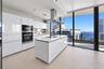 Kitchen featuring high-gloss cabinetry, stone-surfaced center island, stainless steel built-in appliances, stainless steel range hood, and floor-to-ce