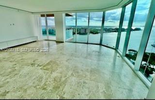Expansive living area featuring floor-to-ceiling glass walls, large-format stone tile flooring, and integrated built-in cabinetry