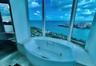 Oval soaking tub with integrated jets, expansive floor-to-ceiling windows, and tile flooring