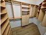 Walk-in closet featuring light-toned custom built-in cabinetry, multiple adjustable shelving units, integrated hanging rods, a five-drawer dresser, an