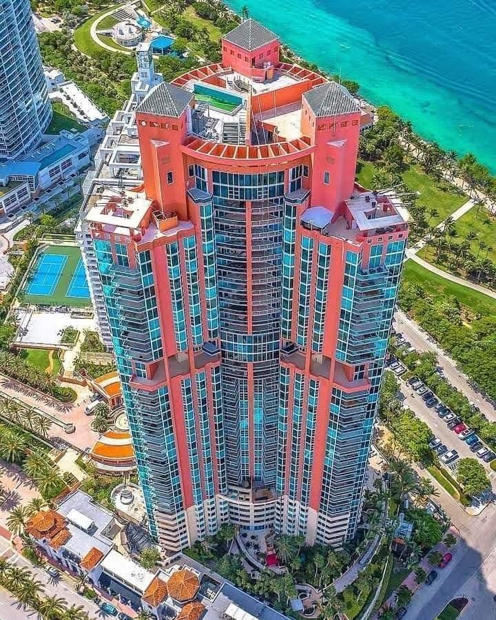 High-rise residential tower featuring a multi-tiered structural design, glass curtain walls, expansive wraparound balconies, rooftop terraces, and a c