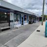 Commercial storefront exterior featuring painted brick facade, retractable fabric awnings, large glass storefront windows, and concrete sidewalk acces