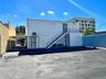 Exterior featuring a paved parking area, covered carport, and metal staircase with iron railings