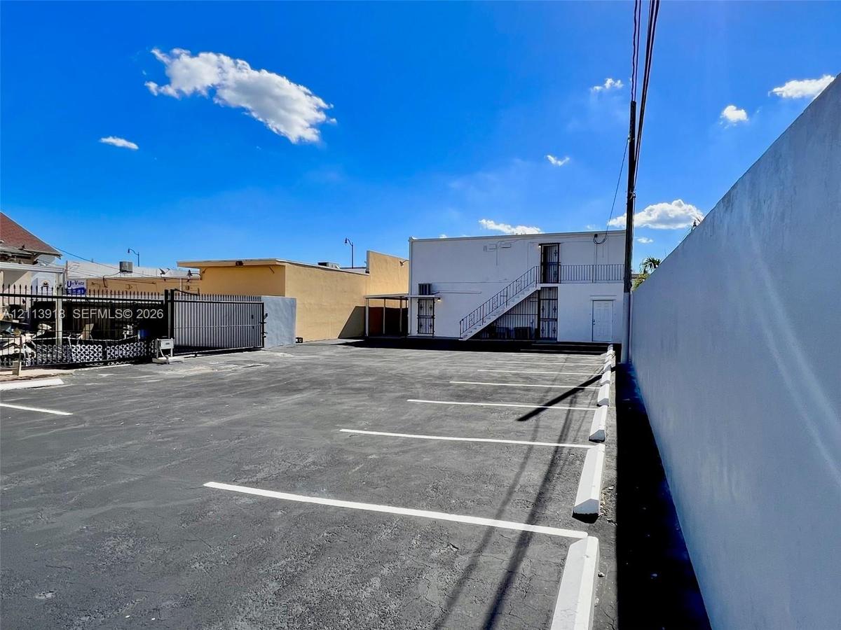 Asphalt-paved parking lot with marked stalls, concrete wheel stops, and a secure perimeter masonry wall