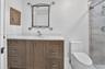 Bathroom vanity featuring light-toned cabinetry, a stone-composite countertop with an integrated rectangular sink, and polished nickel hardware
