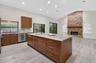 Kitchen featuring a central island with a stone countertop, stained wood cabinetry, recessed lighting, wood-finish flooring, and a floor-to-ceiling br