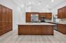 Kitchen featuring custom wood cabinetry, central island with stone countertop, stainless steel appliances, and wood-finish flooring under recessed lig