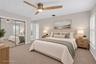 Neutral-toned interior featuring wall-to-wall carpeting, floor-to-ceiling mirrored closet doors, a brushed metal ceiling fan with integrated lighting,