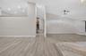Open-concept interior featuring wood-finish flooring, vaulted ceilings, recessed lighting, and a stone-accented hearth