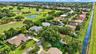 Aerial perspective of property featuring mature canopy trees, tiled roofing, and proximity to canal waterways and golf course grounds