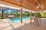 Covered lanai featuring a wood-plank ceiling, brick pillars, and paver flooring, including a screened-in pool with a metal handrail