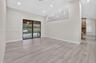 Open living area featuring wood-finish flooring, recessed lighting, high ceilings with architectural cutouts, sliding glass doors, and a brick-accente