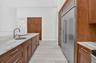 Kitchen featuring wood cabinetry, expansive stone countertops, stainless steel side-by-side refrigerator, under-mount prep sink with high-arc faucet, 