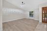 Vaulted ceilings, wood-finish flooring, recessed bay window with plantation shutters, integrated circular flush-mount lighting, and decorative wood-pa