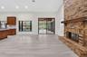 Vaulted ceiling living area featuring a full-height exposed brick fireplace, wood-finish flooring, recessed lighting, and sliding glass doors leading 