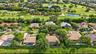 Aerial perspective showcasing a residential property with a shingle roof and a screened-in lanai, situated on a golf course lot featuring mature trees