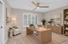 Neutral-toned walls, three-blade wood-finish ceiling fan with integrated lighting, polished stone-finish flooring, and white plantation shutters