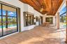 Covered lanai featuring a tongue-and-groove wood ceiling, stamped concrete flooring, brick pillars, and sliding glass door access