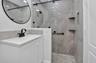 White vanity cabinet with an integrated rectangular sink and matte black faucet, paired with a frameless glass shower enclosure featuring large-format