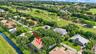 Aerial perspective featuring a multi-pitched shingle roof, screened-in lanai, and landscaped grounds situated on a waterway