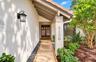 Covered entryway featuring a concrete paver walkway, stucco exterior, decorative wall-mounted light fixture, and double entry doors with vertical glas