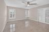 (FAN VIRTUALLY STAGED AS SIMILAR PIECE WILL BE INSTALLED)Large-format neutral tile flooring, triple white plantation shutters, and a modern brushed-ni