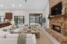 Vaulted ceilings, floor-to-ceiling brick fireplace with a wood mantel, recessed lighting, expansive glass sliding doors, and wood-finish flooring