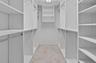Walk-in closet featuring white built-in shelving, adjustable shelf tracks, metal garment rods, and tile flooring