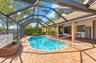 Screened-in patio featuring a paver deck, kidney-shaped pool, brick-clad support columns, and built-in planters