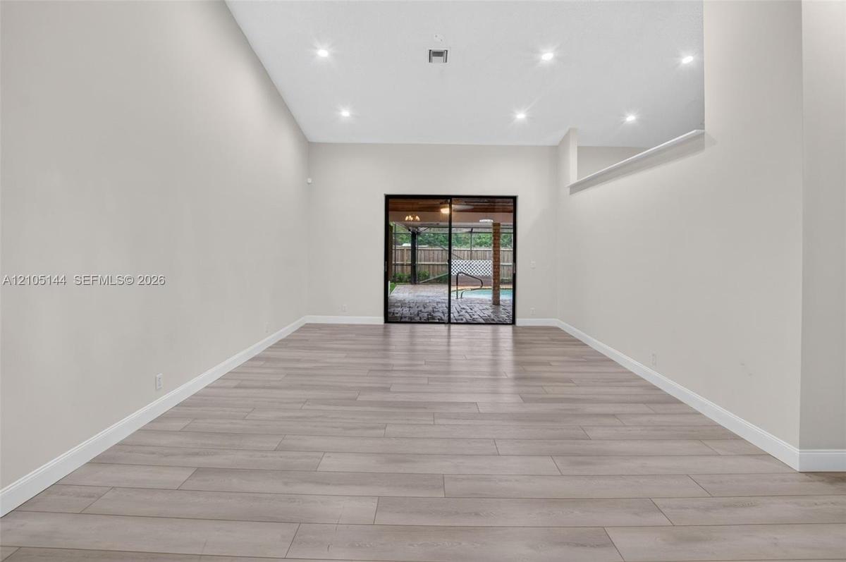 Open interior featuring high ceilings, recessed lighting, wood-finish flooring, and sliding glass doors