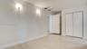 Interior space featuring light-toned wood-finish flooring, neutral walls, two wall-mounted light fixtures, and a white six-panel closet door