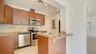 Kitchen featuring flat-panel wood cabinetry, stone countertops, textured stone backsplash, stainless steel appliances, and recessed lighting