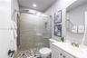 Bathroom featuring a glass-enclosed shower with horizontal wall tile, mosaic floor tiling, built-in recessed shelving, a multi-function shower panel, 