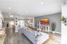 Open-concept living space featuring wood-finish flooring, recessed lighting, and a textured accent wall