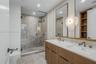 Double vanity featuring wood-finish cabinetry, white countertop, integrated sinks, and dual mirrors