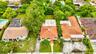 Aerial perspective featuring a terracotta-tiled roofline, concrete walkway, mature landscaping, and an expansive lawn