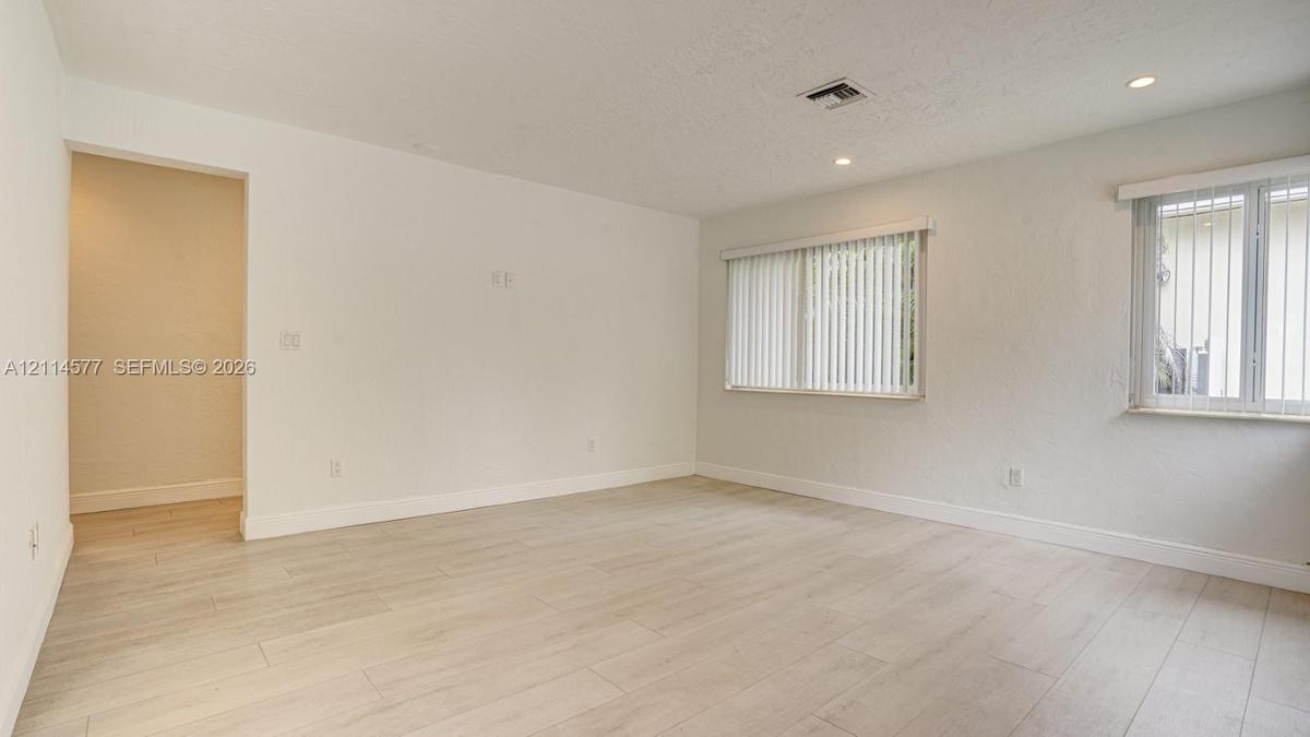 Interior space featuring light-toned wood-finish flooring, recessed lighting, and dual windows with vertical blinds