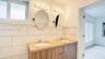 Double vanity with a stone-finish countertop, dual drop-in sinks, wood-finish cabinetry, and ceramic tile wall accents