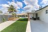 Backyard featuring a paved stone patio, artificial turf lawn, swimming pool, tension shade sail, and perimeter wood privacy fencing