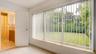 Expansive multi-pane window with vertical blinds, light-toned tile flooring, and a solid-core interior door leading to a bathroom featuring a wooden v
