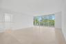 Open-concept interior featuring large-format tile flooring, floor-to-ceiling glass sliding doors, and neutral wall finishes