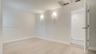 Neutral interior space featuring wood-finish flooring, dual wall-mounted light fixtures, and a six-panel interior door