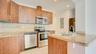 Kitchen featuring wood-finish cabinetry, stone-surface countertops, stone tile backsplash, and stainless steel appliances