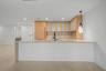 Kitchen featuring wood cabinetry with glass-panel upper doors, a stone-finish waterfall edge island, a matte black high-arch faucet, integrated applia