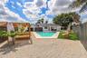 Private backyard featuring an in-ground swimming pool, custom wood pergola, gravel ground cover, artificial turf lawn, and perimeter privacy fencing
